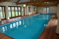 Large indoor pool with hardwood timber decking and matching roof trusses